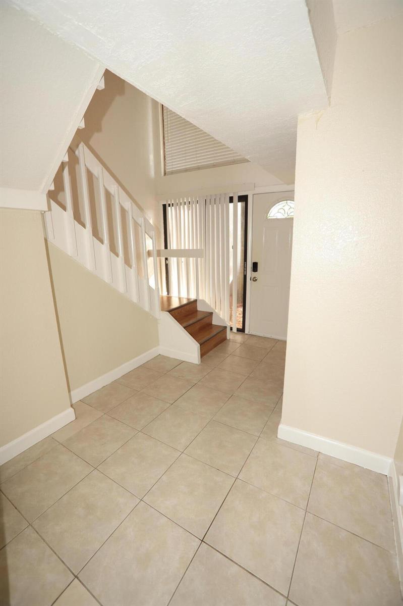 An entryway features light-colored tile flooring, a white staircase, and a white front door — 1265 The 12th Fairway, Wellington FL 33414, WELLINGTON, FL