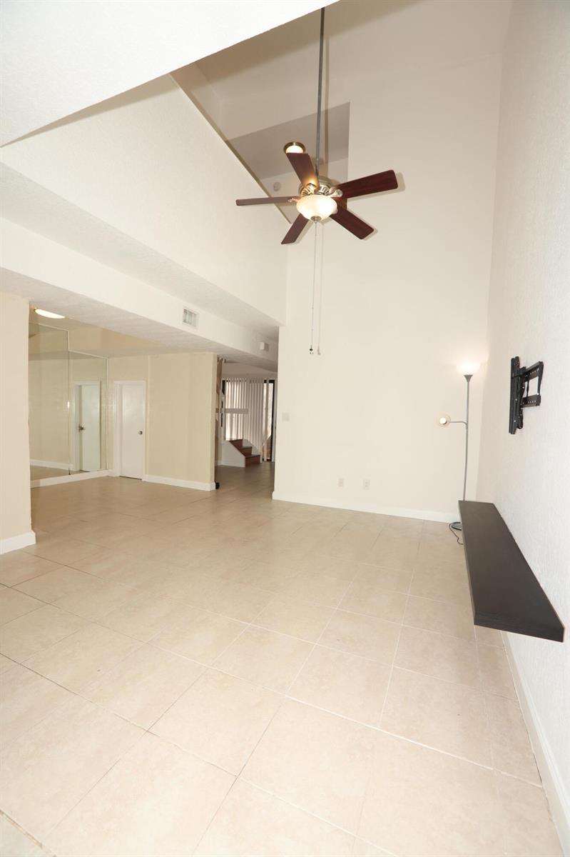 A living room with high ceilings, a ceiling fan, tile flooring, and a wall-mounted shelf — 1265 The 12th Fairway, Wellington FL 33414, WELLINGTON, FL