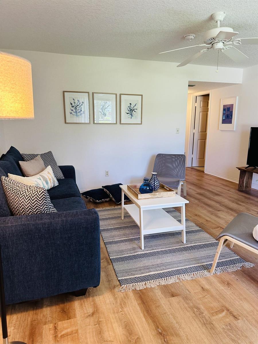 A living room features a blue sofa, a white coffee table, and a patterned area rug — 80 Crooked Tree Lane, Vero Beach FL 32962, VERO BEACH, FL