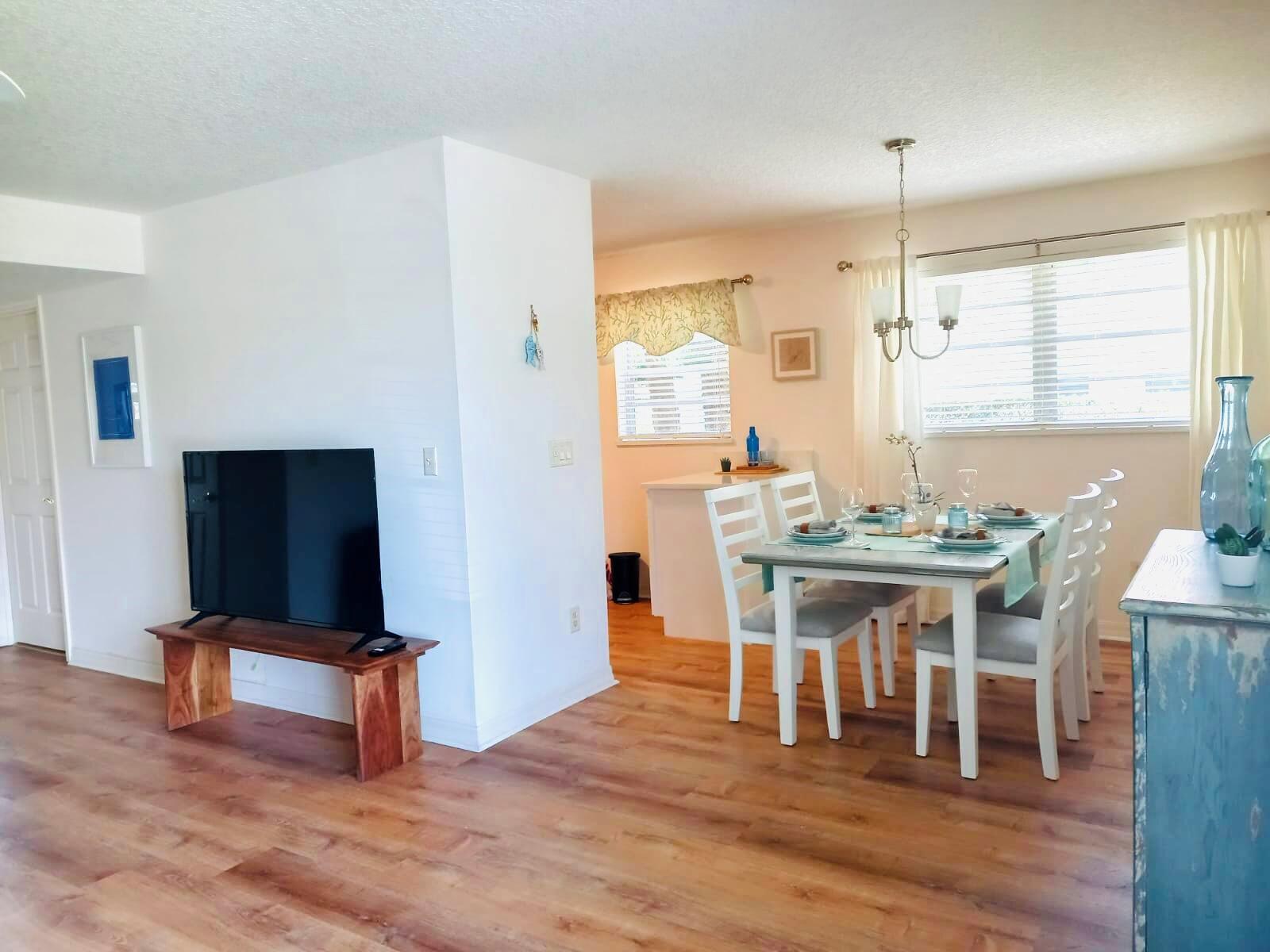 A dining area with a white table and chairs sits adjacent to a living room — 80 Crooked Tree Lane, Vero Beach FL 32962, VERO BEACH, FL