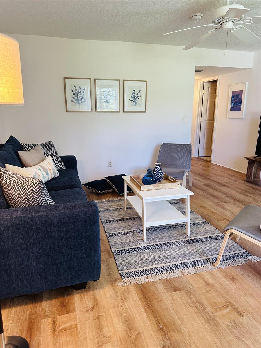 A living room features a navy blue sofa, a white coffee table, and wood flooring — 80 Crooked Tree Lane, Vero Beach FL 32962, VERO BEACH, FL