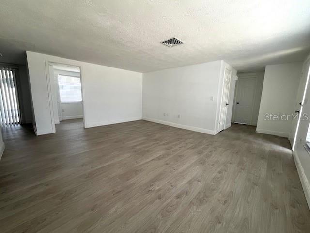 An empty room with light wood-look flooring, white walls, and a doorway leading to another room — 6646 ALBEMARLE PARKWAY, NEW PORT RICHEY, FL