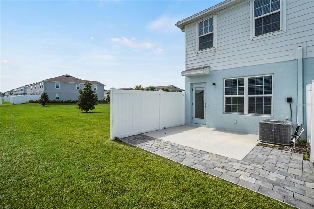 A paved patio sits beside a light blue house with a white vinyl privacy fence — 14229 CRIMSON AVENUE, LAKEWOOD RANCH, FL