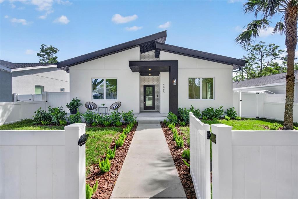 A modern white house with a dark roof and a central entryway behind a fence — 4365 IRIS STREET N, ST PETERSBURG, FL
