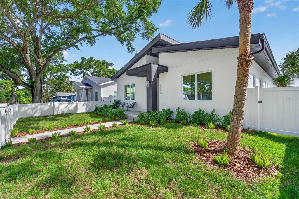 A modern white house with a dark roof and a fenced front yard — 4365 IRIS STREET N, ST PETERSBURG, FL