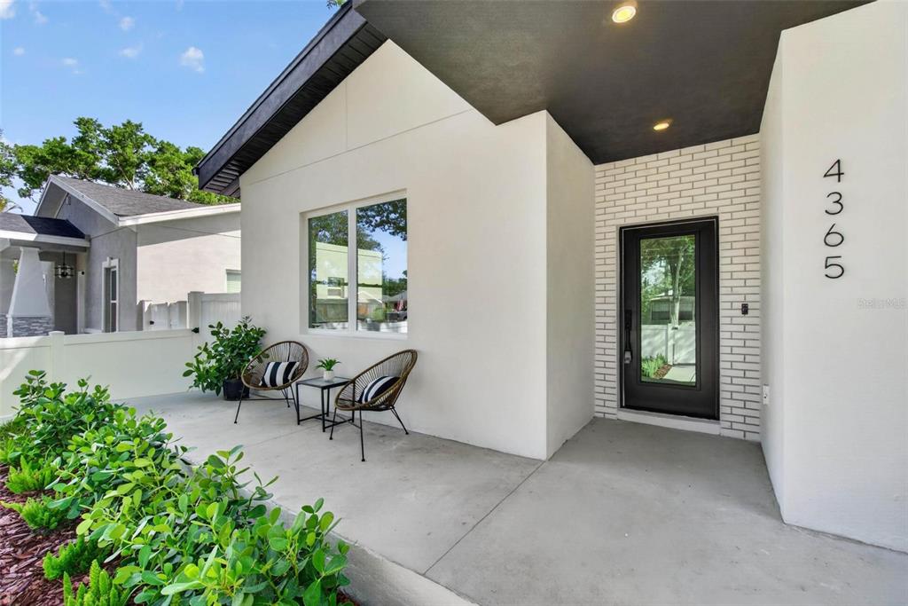 A modern house exterior features a white facade, a black door, and a concrete porch — 4365 IRIS STREET N, ST PETERSBURG, FL