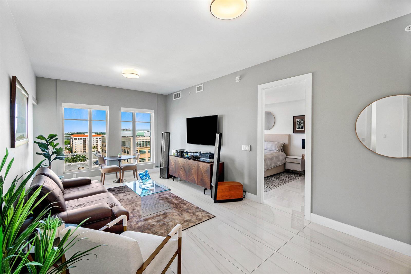 A living room with a brown leather sofa, glass coffee table, and view of buildings — 155 E Boca Raton Road # 1119, Boca Raton FL 33432, BOCA RATON, FL