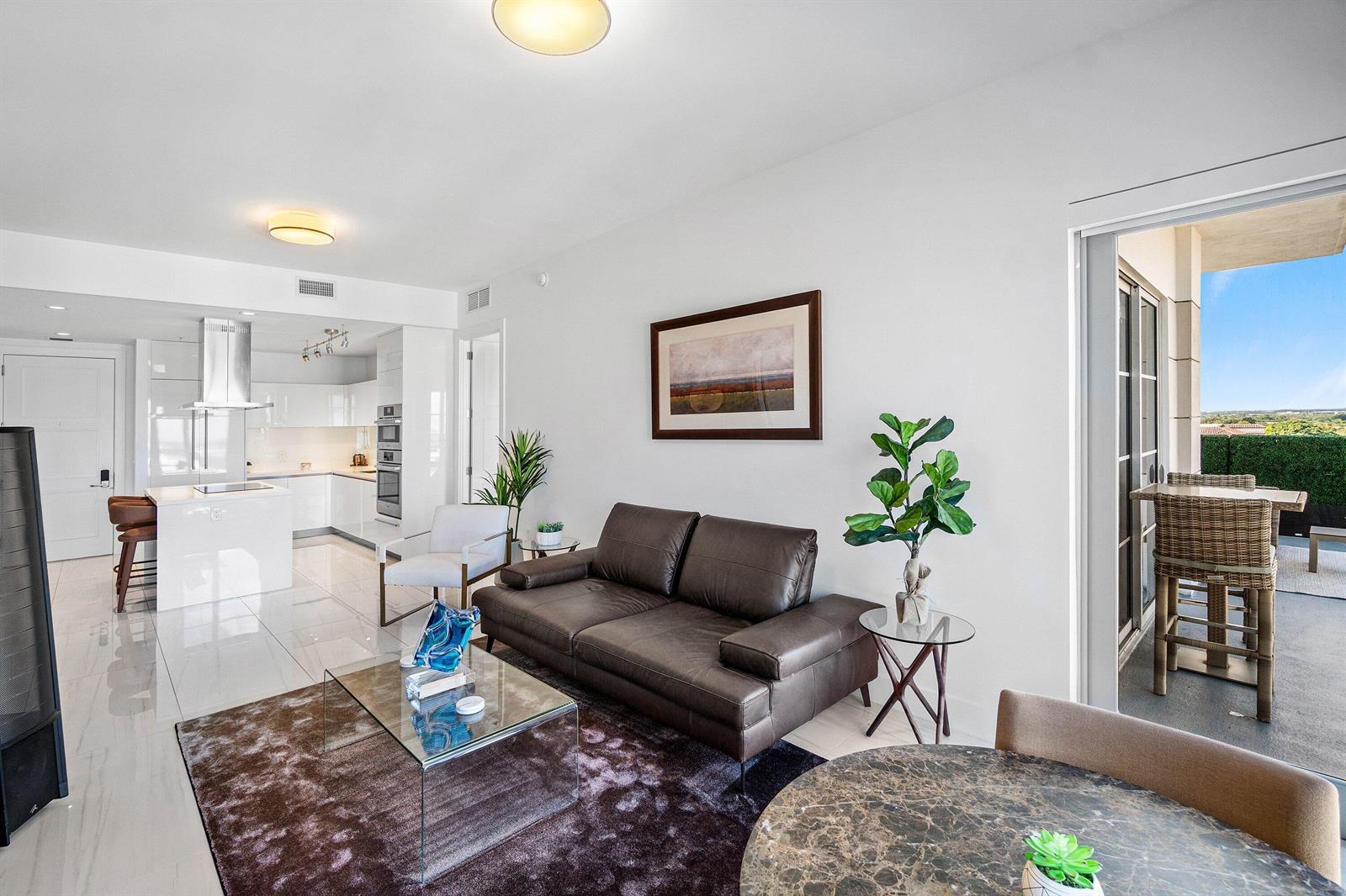 A modern living room with a brown leather sofa, glass coffee table, and open kitchen — 155 E Boca Raton Road # 1119, Boca Raton FL 33432, BOCA RATON, FL