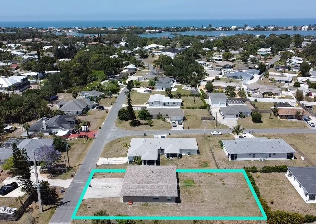 An aerial view shows a single-story house with a large, vacant lot outlined in teal — 100 CHARLES DRIVE, NOKOMIS, FL