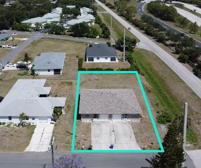 An aerial view shows a duplex with a concrete driveway and a fenced backyard — 100 CHARLES DRIVE, NOKOMIS, FL