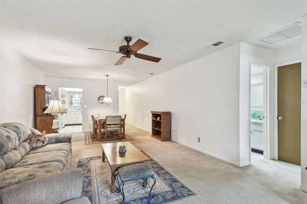 A living room with beige carpet, a ceiling fan, and an adjacent dining area — 11200 102ND AVENUE UNIT 48, SEMINOLE, FL