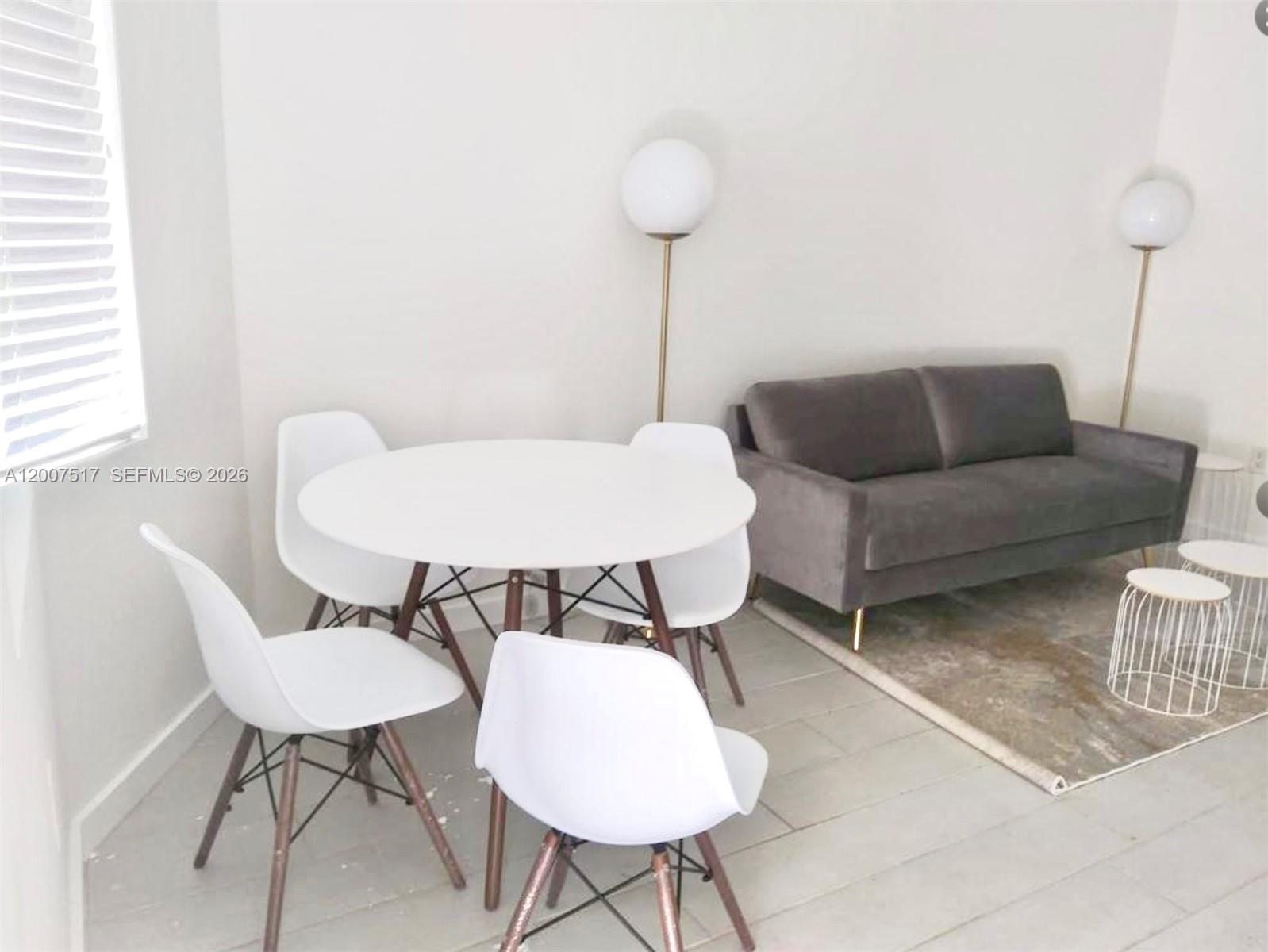 A dining area with a round white table and four chairs sits beside a gray sofa — 740 Meridian Ave # 17, Miami Beach FL 33139, MIAMI BEACH, FL