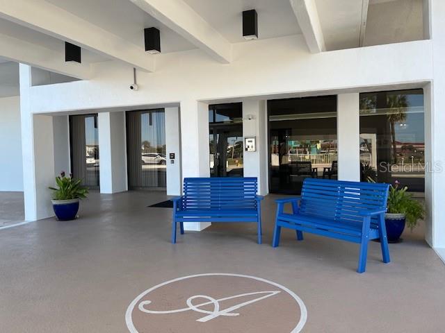 Two blue benches sit on a covered patio in front of a building entrance — 2828 N ATLANTIC AVENUE UNIT 1601, DAYTONA BEACH, FL