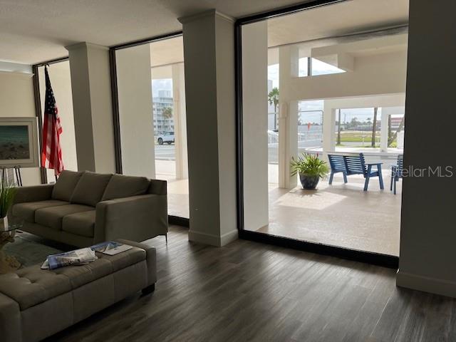A living room with a sofa and ottoman opens to a patio with outdoor seating — 2828 N ATLANTIC AVENUE UNIT 1601, DAYTONA BEACH, FL