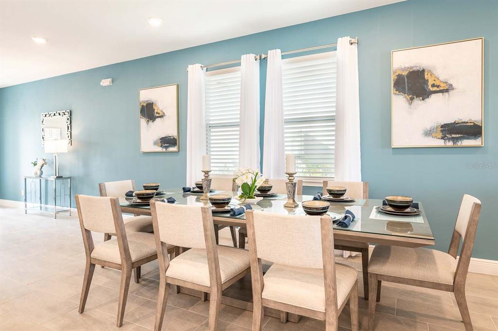 A dining room features a glass-topped table, upholstered chairs, and blue walls with framed art — 428 SOUTHFIELD STREET, KISSIMMEE, FL