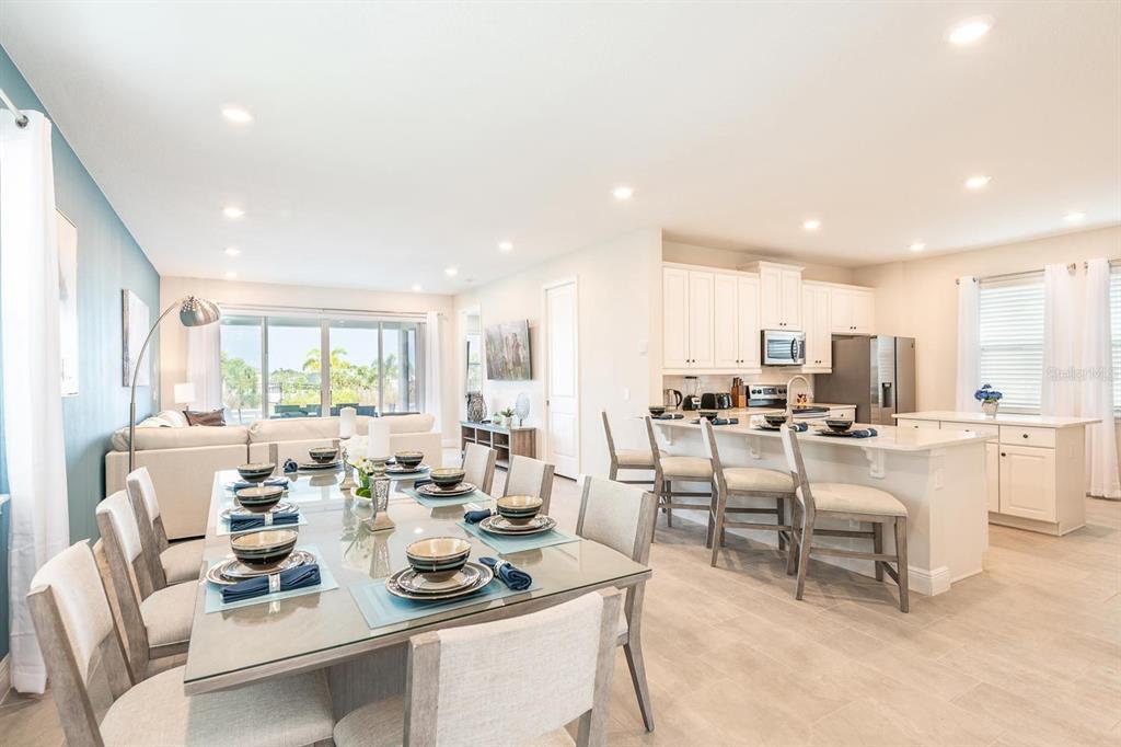 An open-concept dining area and kitchen featuring a glass table, white cabinetry, and tile floors — 428 SOUTHFIELD STREET, KISSIMMEE, FL