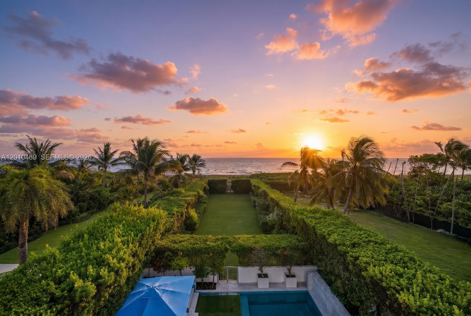 An aerial view shows a backyard lawn, swimming pool, and palm trees facing the ocean — 7815 Atlantic Way, Miami Beach FL 33141, MIAMI BEACH, FL