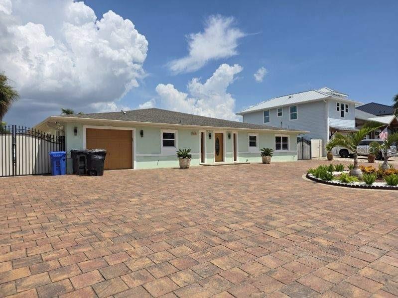 A light green house with a paved driveway and a two-car garage under a cloudy sky — 3927 E EDEN ROC CIRCLE, TAMPA, FL