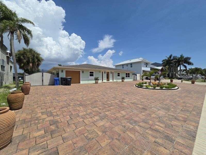 A light green single-story house features a large paver driveway and decorative clay pots — 3927 E EDEN ROC CIRCLE, TAMPA, FL