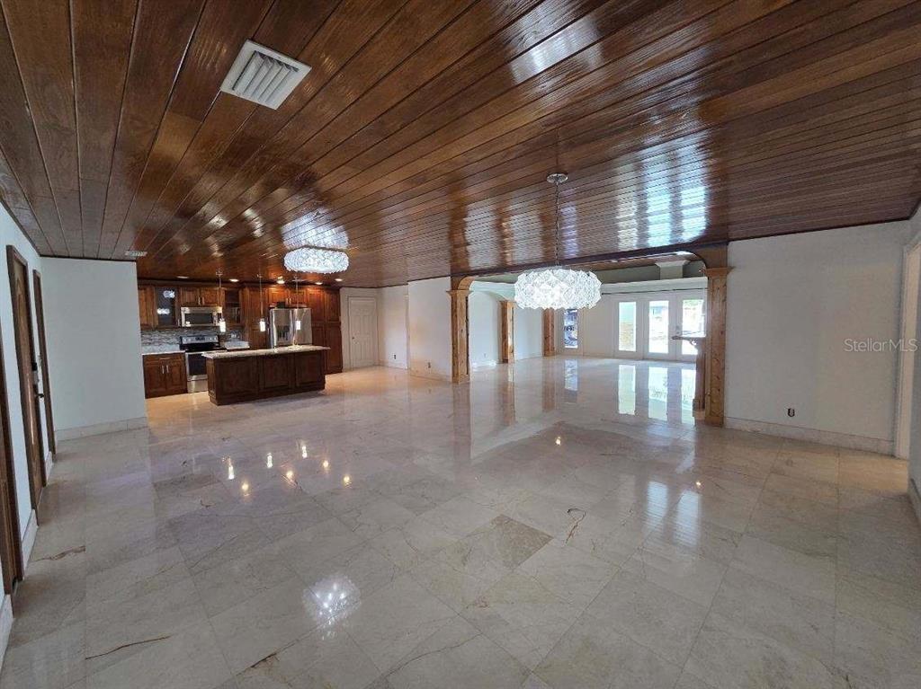 A large open-concept room features a wood-paneled ceiling, marble tile flooring, and a kitchen — 3927 E EDEN ROC CIRCLE, TAMPA, FL