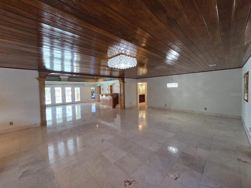 A large room with a glossy wood-paneled ceiling, marble floors, and a built-in bar area — 3927 E EDEN ROC CIRCLE, TAMPA, FL