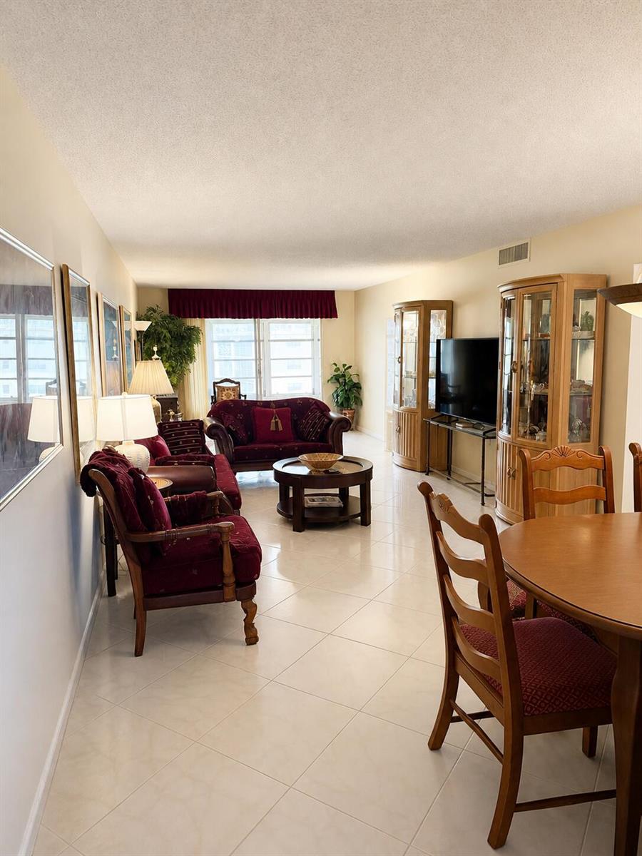 A living room with tile floors, burgundy furniture, and two wooden display cabinets — 4037 Guildford C, Boca Raton FL 33434, BOCA RATON, FL