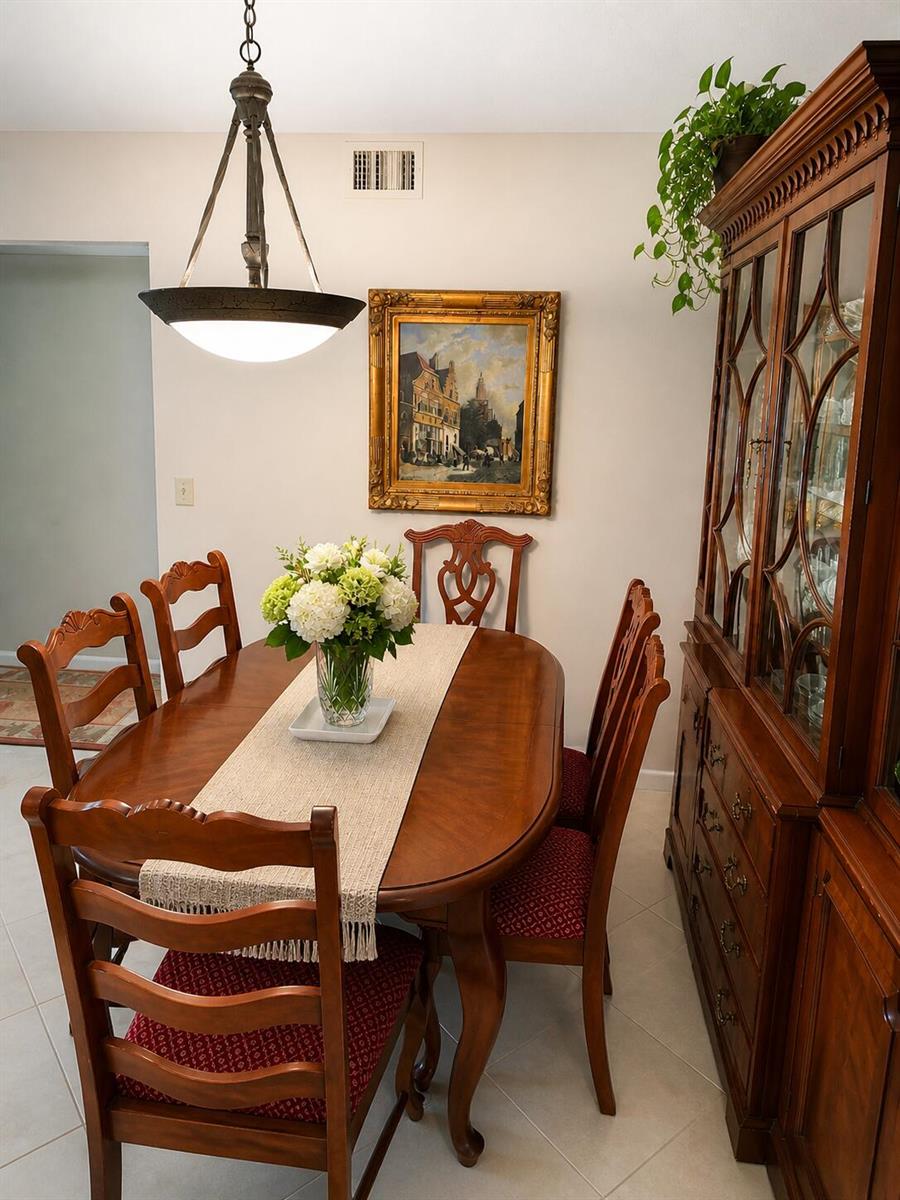 A dining room features a wooden table, chairs with red patterned cushions, and a china cabinet — 4037 Guildford C, Boca Raton FL 33434, BOCA RATON, FL