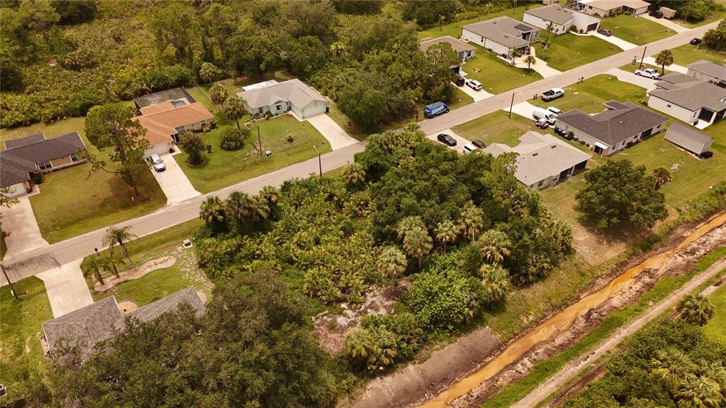 An aerial view shows a vacant wooded lot situated between suburban houses and a canal — Lot 17 & 18 TUPELO AVENUE, NORTH PORT, FL