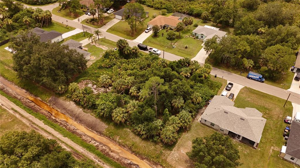 An aerial view shows a vacant, wooded lot situated between several suburban residential homes — Lot 17 & 18 TUPELO AVENUE, NORTH PORT, FL
