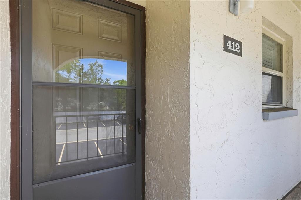 A view of an apartment entrance with a screen door and the number 412 — 7701 STARKEY ROAD UNIT 412, SEMINOLE, FL