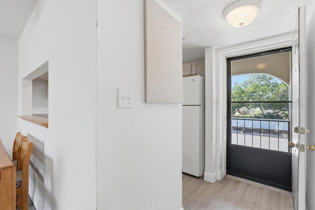 A view of a kitchen area with a white refrigerator and a door leading outside — 7701 STARKEY ROAD UNIT 412, SEMINOLE, FL