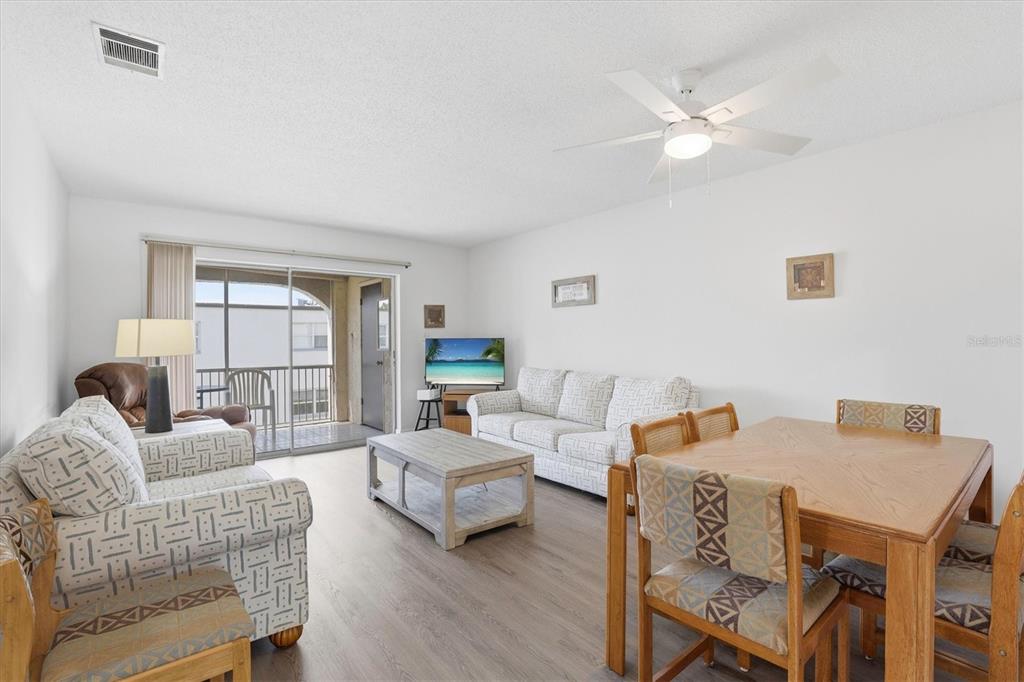 A living and dining area features light wood flooring, patterned sofas, and a sliding glass door — 7701 STARKEY ROAD UNIT 412, SEMINOLE, FL
