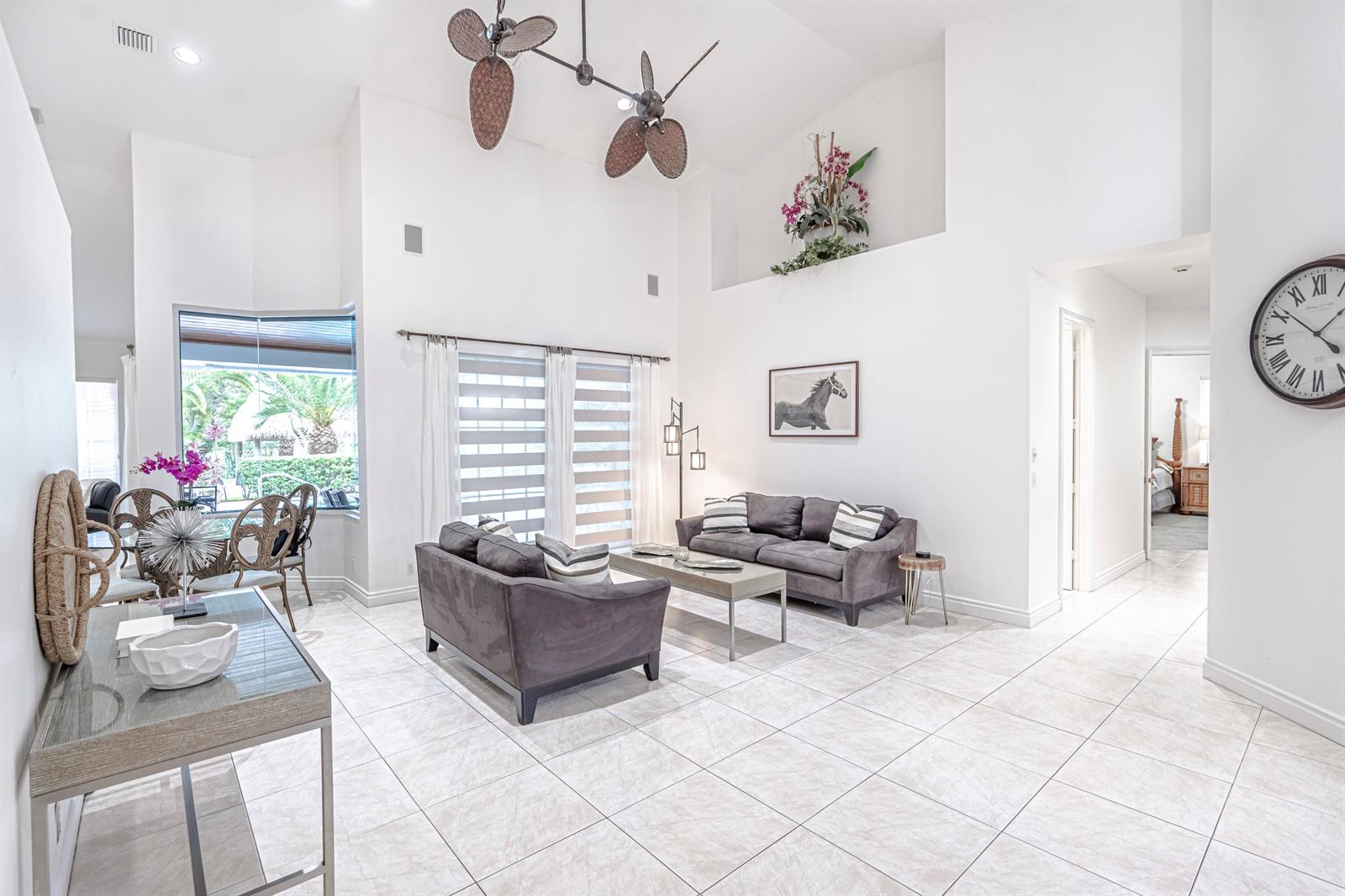 A bright living room features white walls, tile flooring, two gray sofas, and high ceilings — 15350 Take Off Place, Wellington FL 33414, WELLINGTON, FL