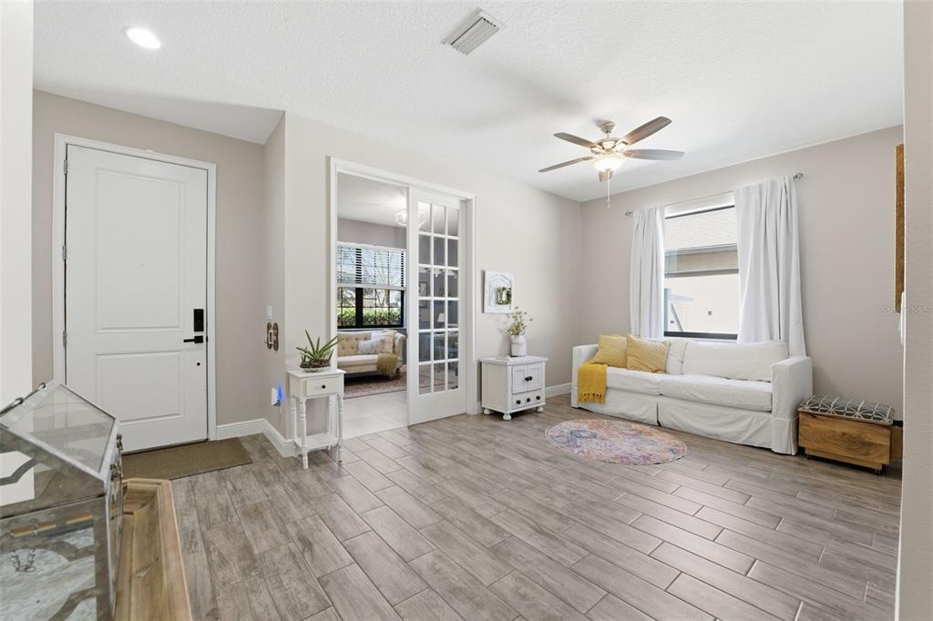 A living room features light tile floors, a grey sectional sofa, and sliding glass doors — 8328 AUBURN RISE COURT, LAND O LAKES, FL