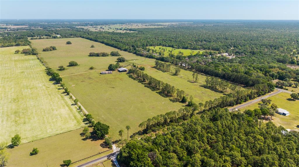 An aerial view shows a large, grassy rural property with scattered trees and buildings — 19355 SW 25TH PLACE, DUNNELLON, FL