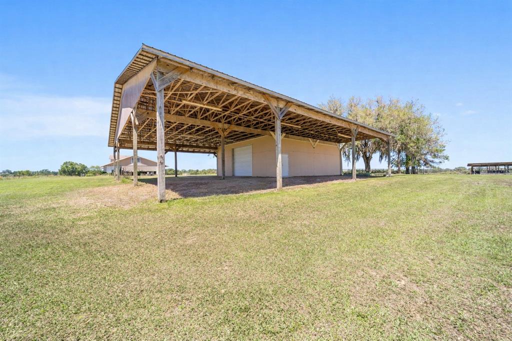 A large, open-sided pole barn with a metal roof stands in a grassy field — 19355 SW 25TH PLACE, DUNNELLON, FL