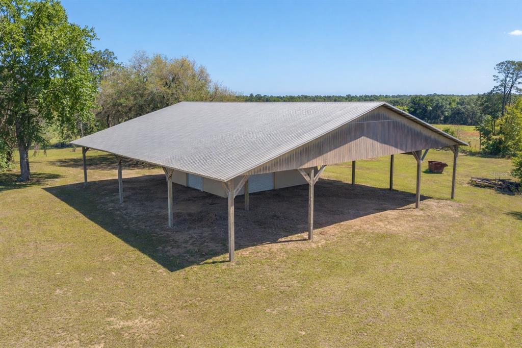 An aerial view of a large metal-roofed pole barn structure situated in a grassy field — 19355 SW 25TH PLACE, DUNNELLON, FL