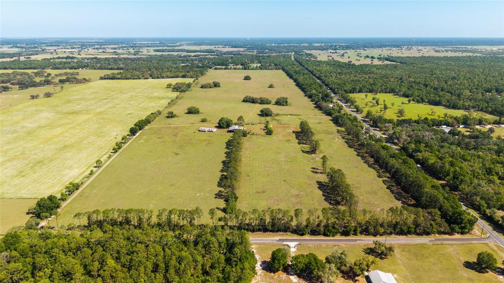 An aerial view shows a large, fenced pasture with a house and scattered trees — 19355 SW 25TH PLACE, DUNNELLON, FL