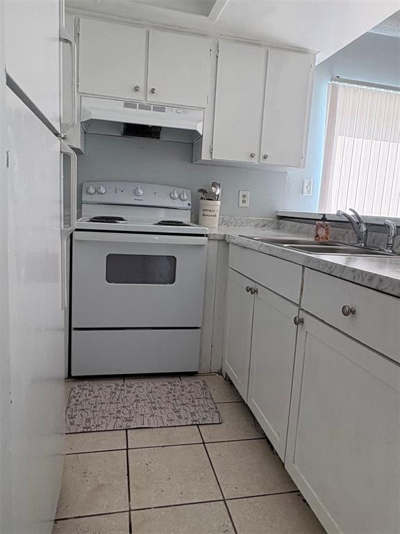 A kitchen features white cabinets, a white stove, and a sink with a tiled floor — 13045 LONDONDARY PLACE, TAMPA, FL