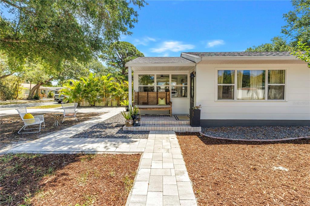 A white house features a covered front porch with a wooden bench and a stone walkway — 798 45TH AVENUE N, ST PETERSBURG, FL