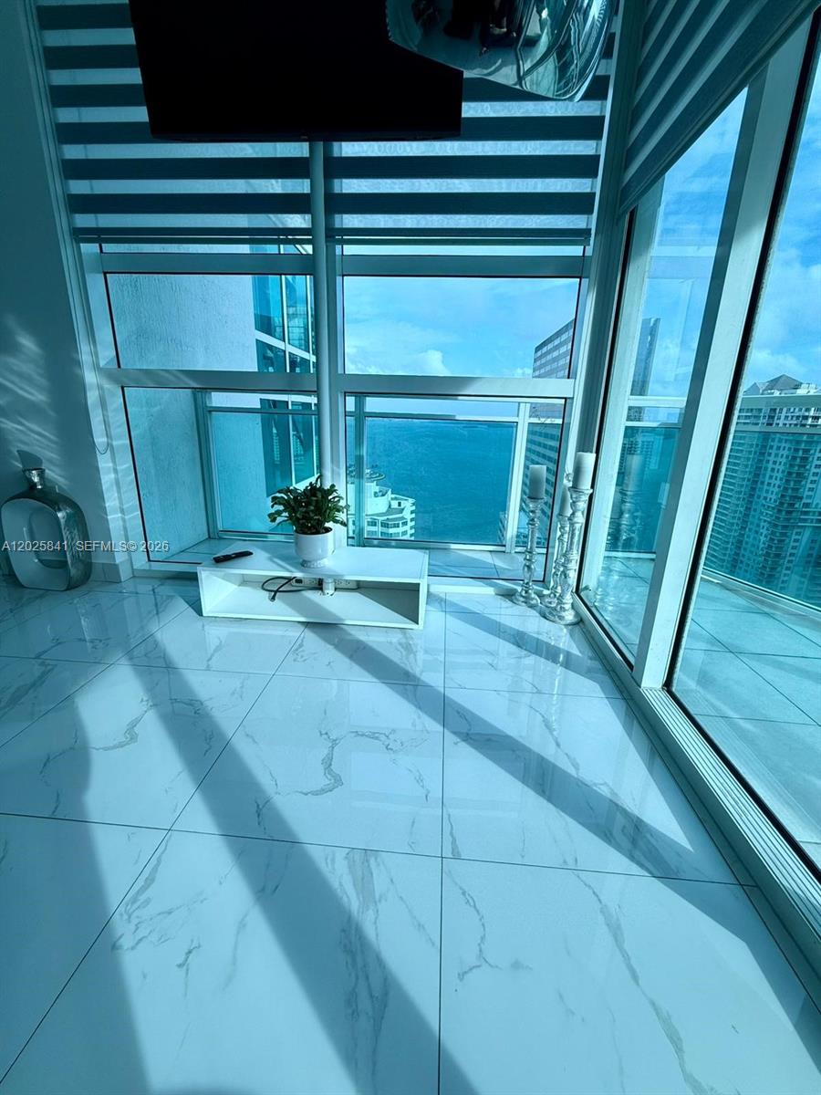 A bright room features white marble floors, floor-to-ceiling windows, and a view of water — 951 Brickell Ave # 2810, Miami FL 33131, MIAMI, FL