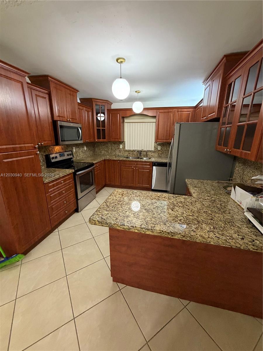 A kitchen features cherry wood cabinets, granite countertops, stainless steel appliances, and tile flooring — 3541 SW 125th Ct, Miami FL 33175, MIAMI, FL