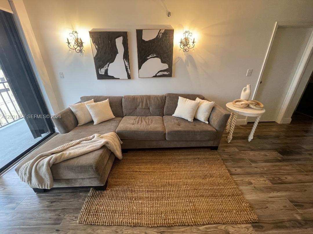 A living room features a brown sectional sofa, a jute rug, and two wall sconces — 2625 Collins Ave # 502, Miami Beach FL 33140, MIAMI BEACH, FL