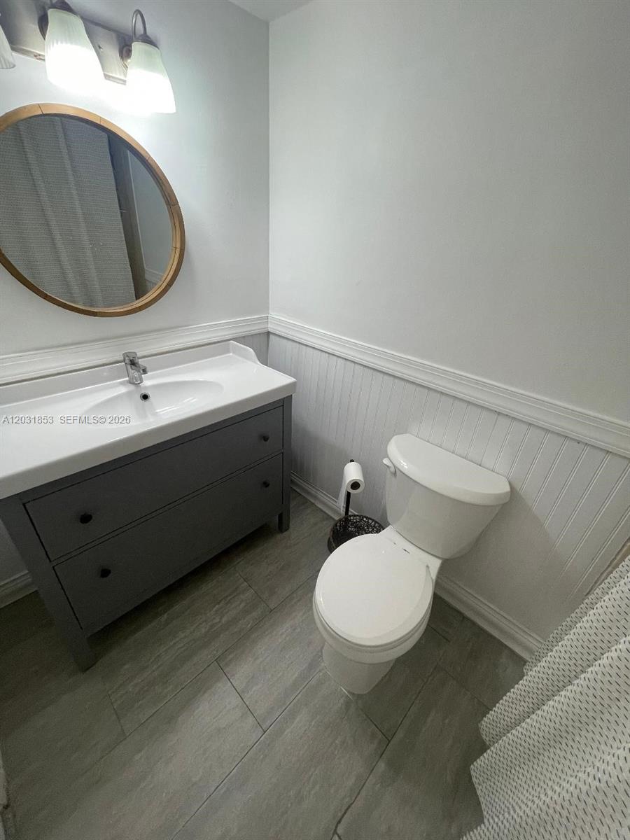 A bathroom features a gray vanity, a round mirror, and a white toilet — 2625 Collins Ave # 502, Miami Beach FL 33140, MIAMI BEACH, FL