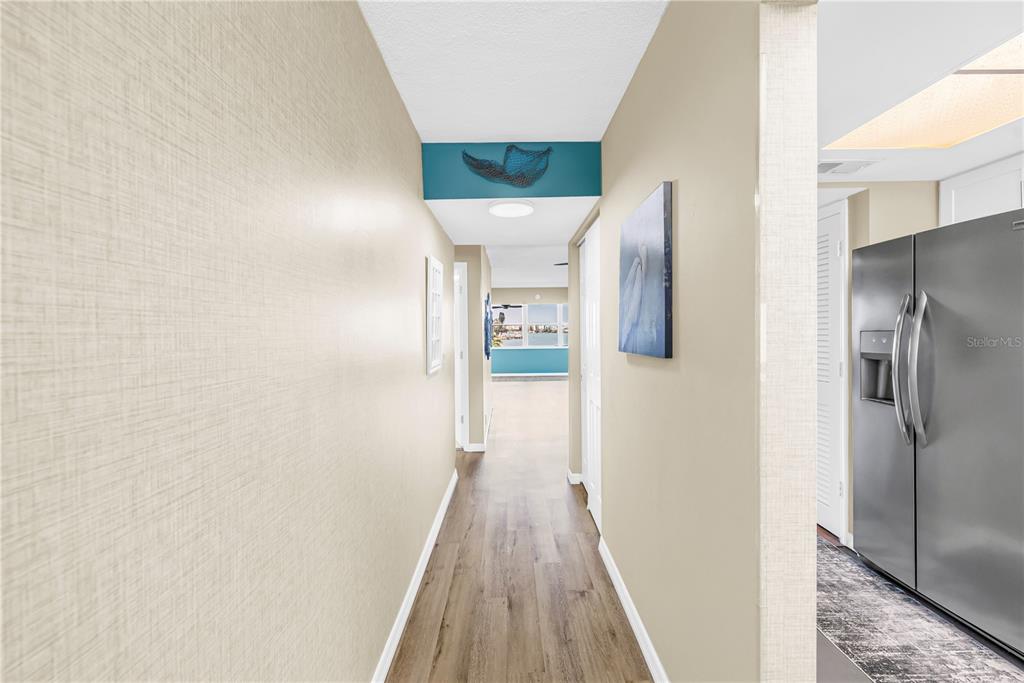 A hallway with wood-look flooring leads toward a bright room with a view — 1868 SHORE DRIVE S UNIT 212, SOUTH PASADENA, FL
