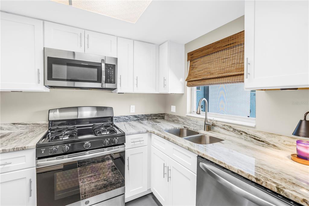 A kitchen featuring white cabinets, stainless steel appliances, and marbled countertops — 1868 SHORE DRIVE S UNIT 212, SOUTH PASADENA, FL