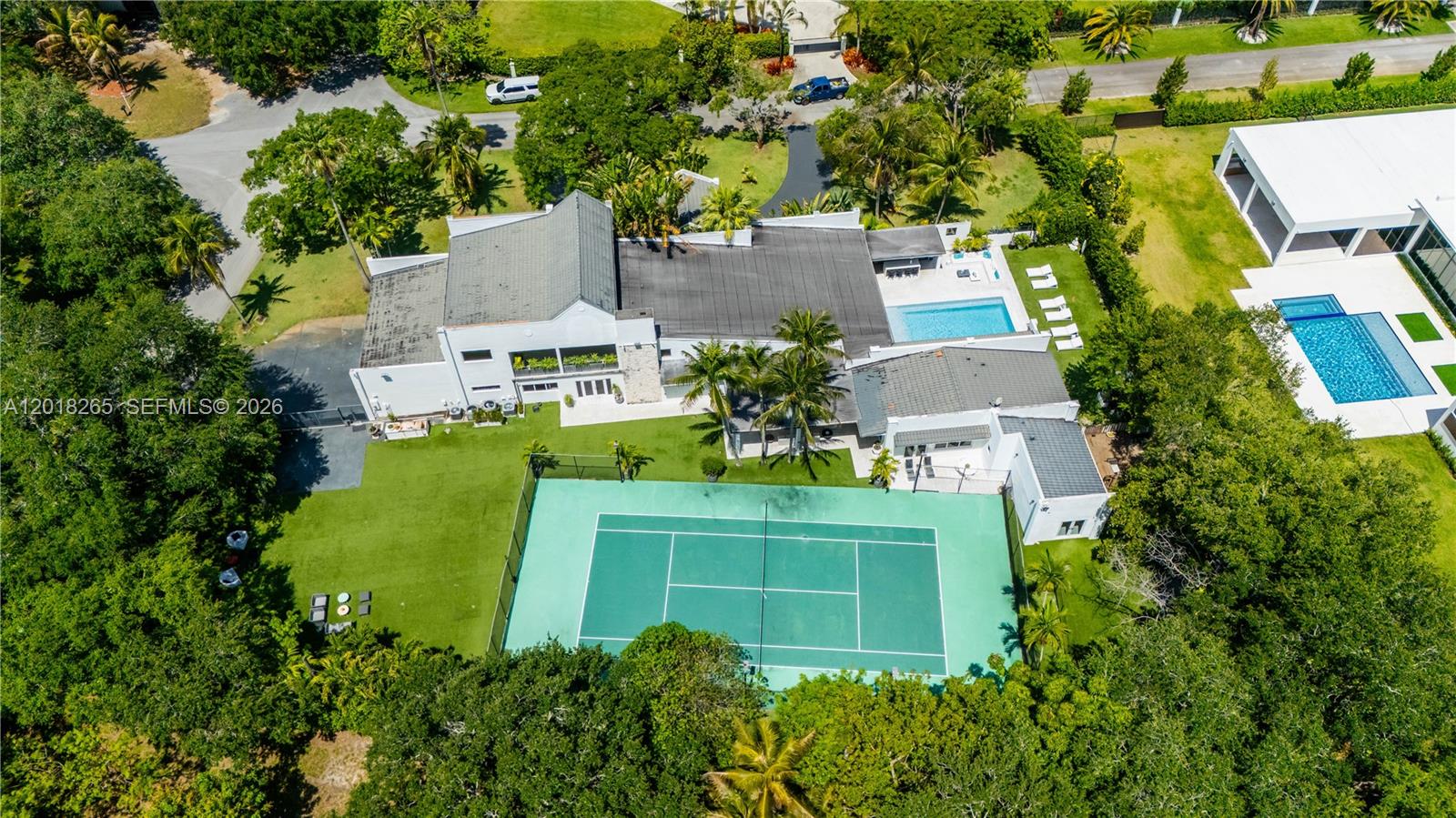 An aerial view shows a house with a tennis court, swimming pool, and surrounding trees — 9715 SW 89th Ct, Miami FL 33176, MIAMI, FL