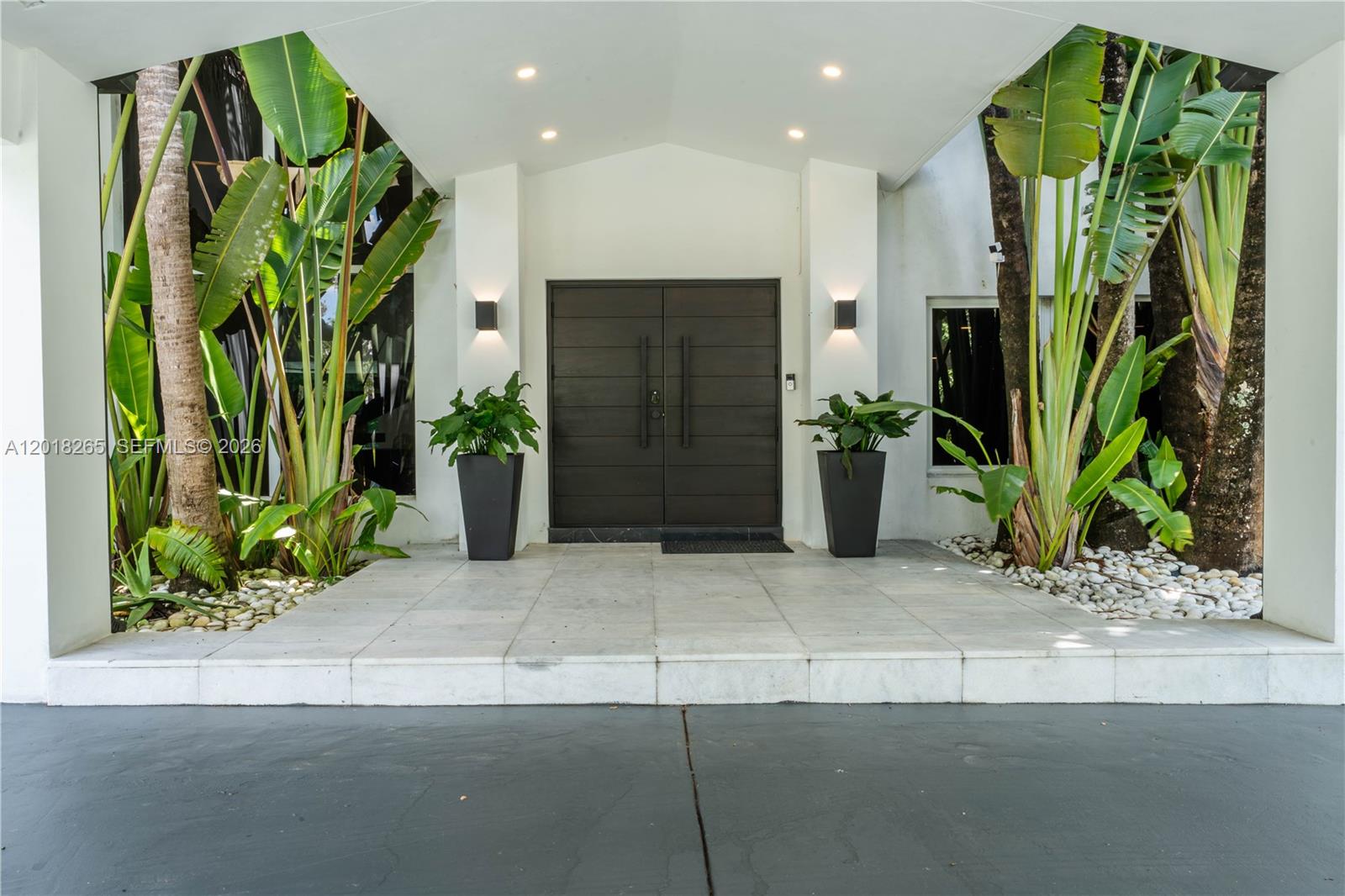 A modern home entrance features double doors, large potted plants, and a covered stone porch — 9715 SW 89th Ct, Miami FL 33176, MIAMI, FL