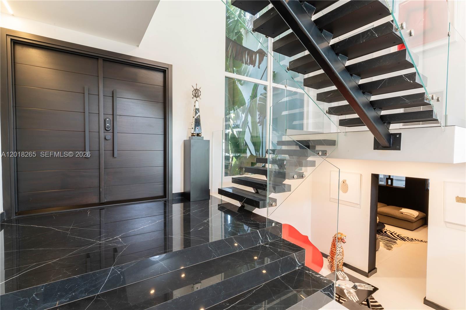 A modern entryway features black marble stairs, a dark wood door, and a floating staircase — 9715 SW 89th Ct, Miami FL 33176, MIAMI, FL