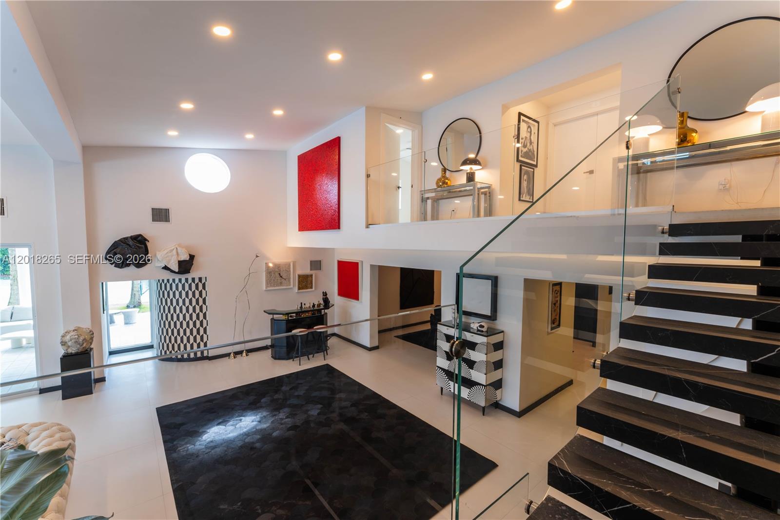 A modern, multi-level living area features a glass staircase, black-and-white accents, and high ceilings — 9715 SW 89th Ct, Miami FL 33176, MIAMI, FL